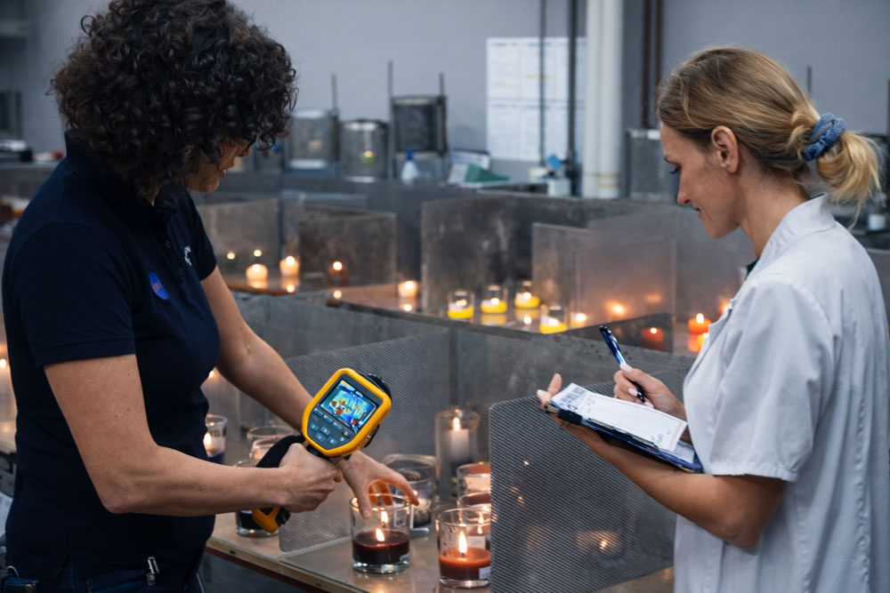 Staff members measure the temperature of the candle flames